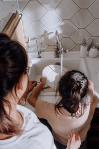 Mother overseeing child washing dishes